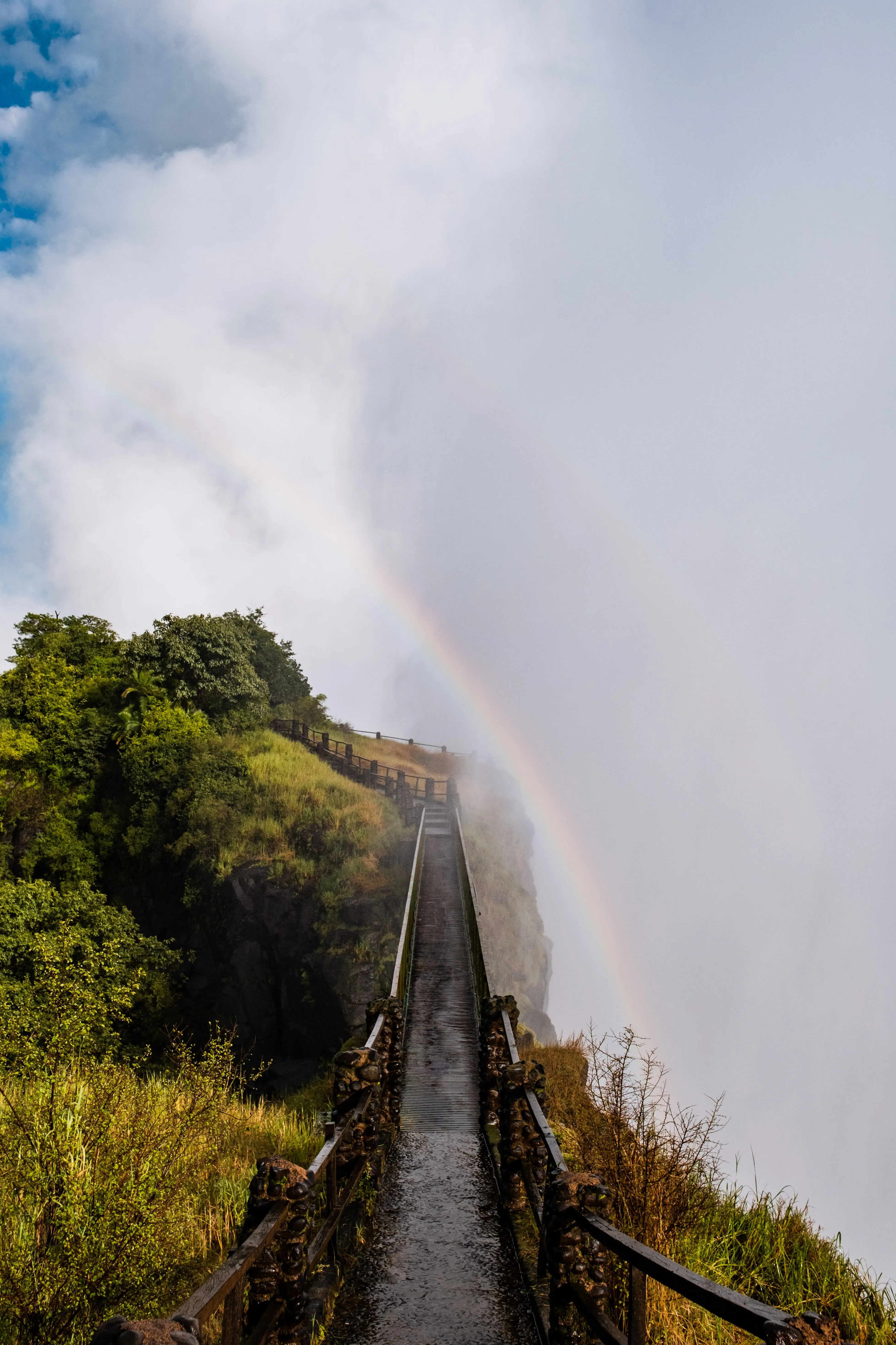 Boardwalk leading into the mist and rainbow at Victoria Falls